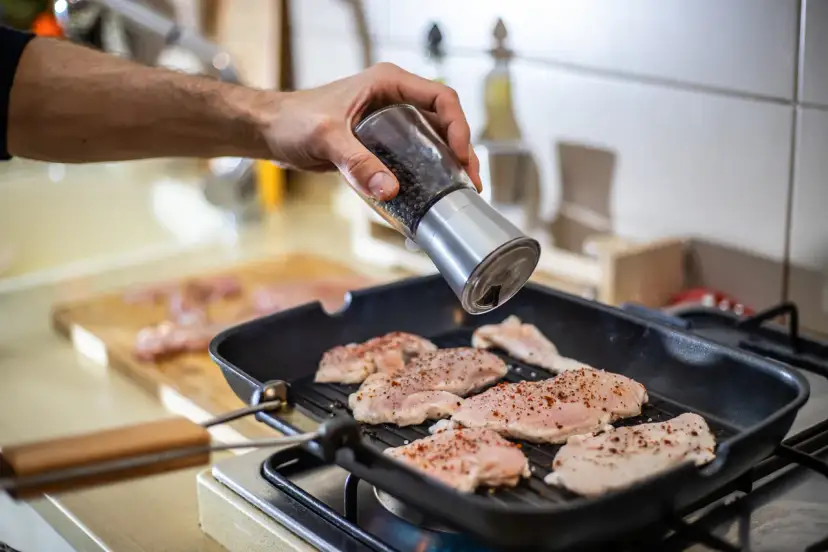 Doprawianie piersi kurczaka pieprzem przed smażeniem. Kluczowe jest, jak długo smażyć pierś z kurczaka, by była soczysta.
