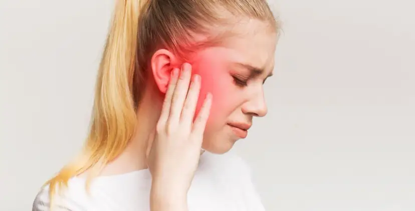 Kobieta z opuchlizną i zaczerwienieniem w okolicy ucha, wskazującym na zapalenie nerwu trójdzielnego.