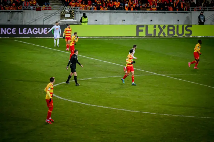 Piłkarze w czerwono-żółtych strojach na boisku. Kto wymyślił piłkę nożną? To pytanie pozostaje bez odpowiedzi, ale gra trwa!