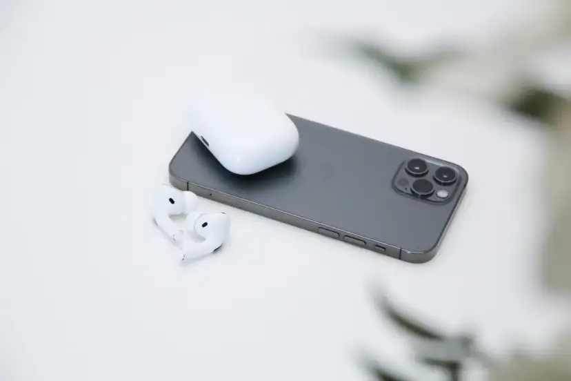 AirPods und Ladecase liegen neben einem Smartphone.