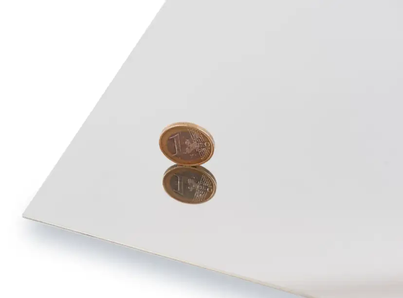 Błyszcząca powierzchnia, efekt polerowania stali nierdzewnej, odbija monetę euro.