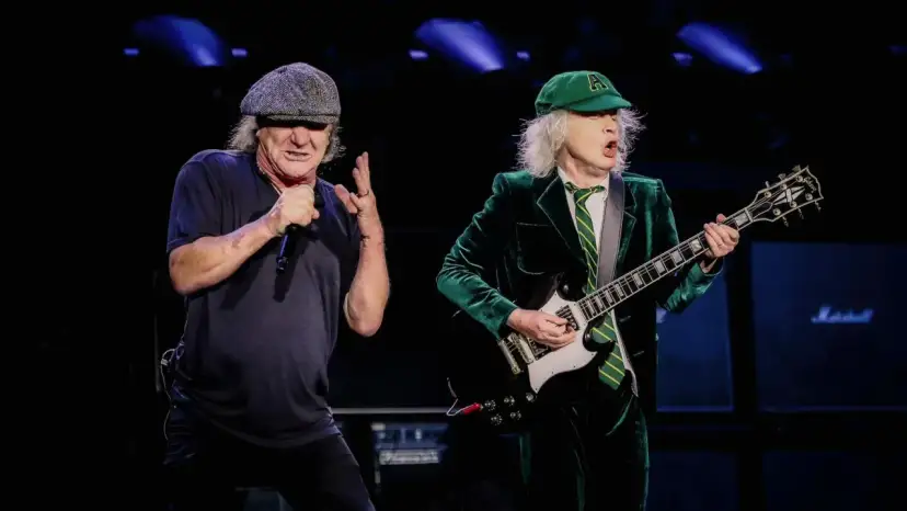 Brian Johnson i Angus Young, legendarny skład AC/DC, na scenie. Brian śpiewa do mikrofonu, Angus gra na gitarze.