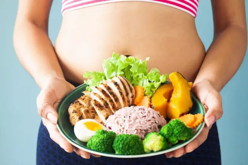 Zdrowa dieta to klucz do tego, jak zgubić oponkę z brzucha. Na talerzu grillowany kurczak, ryż, jajko i warzywa.