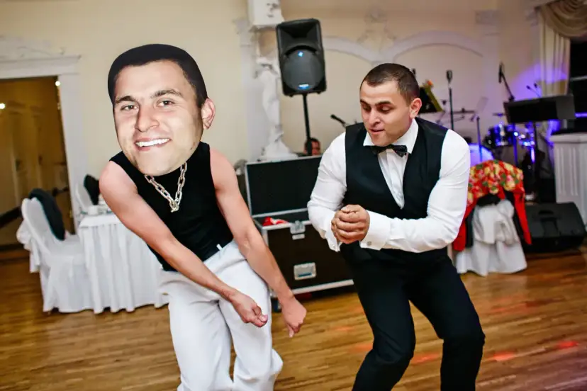 Dwóch mężczyzn tańczy na imprezie. Jeden ma na sobie czarną koszulkę i białe spodnie, a drugi białą koszulę i czarny garnitur. Zabawy taneczne na imprezę w pełni!