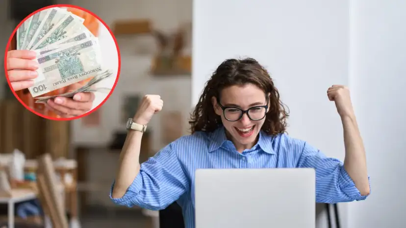 Radość z zarobków! Kobieta cieszy się, widząc na ekranie laptopa, ile płatny jest staż. W tle widać stos banknotów.