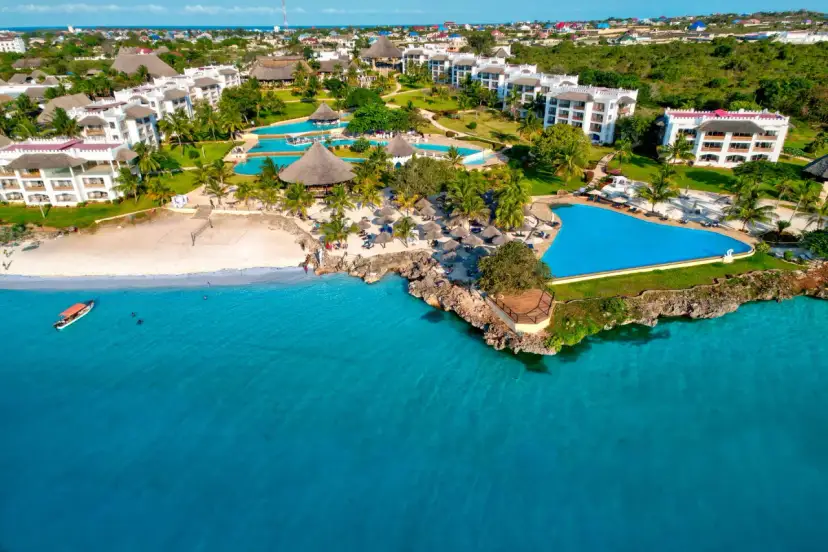 Widok z samolotu na tropikalny kurort na Zanzibarze z białymi budynkami, basenami i plażą nad turkusowym oceanem.
