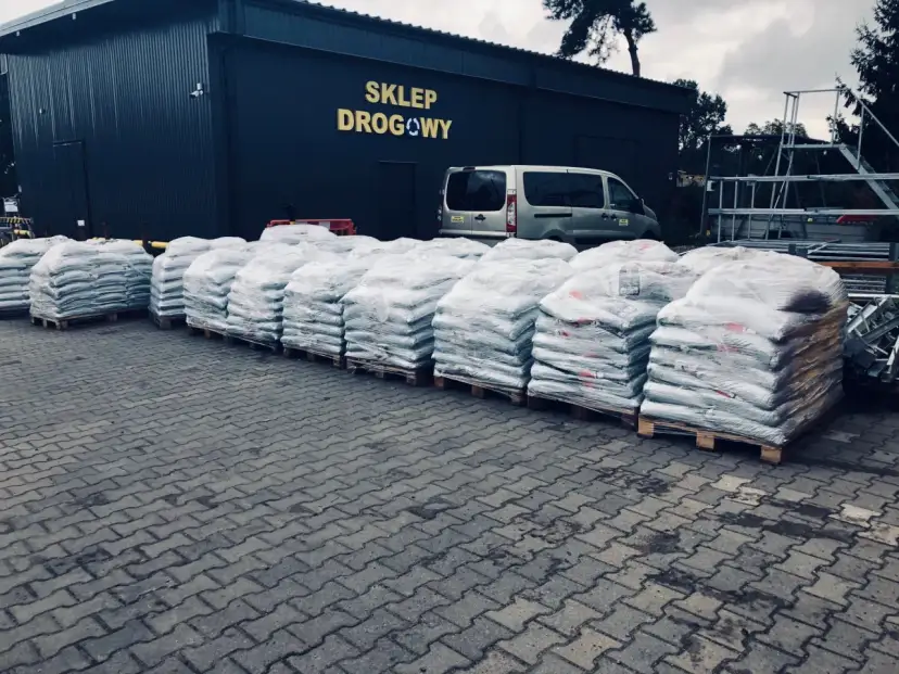 Silosy z materiałami drogowymi przed sklepem drogowym.