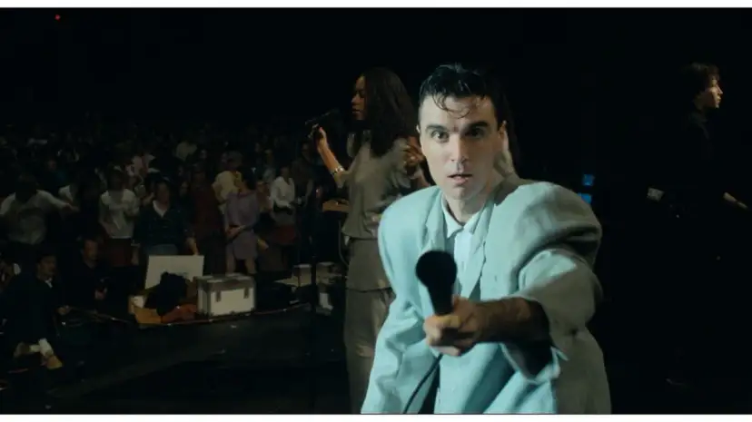 David Byrne z The Cult - Be Free, śpiewa do mikrofonu na tle tłumu.