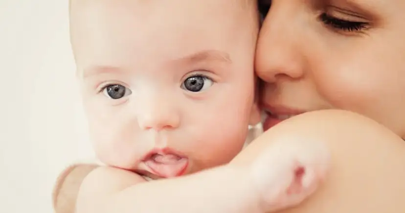Zbliżenie na twarz niemowlaka i matki, podkreślające bliskość i czułość.