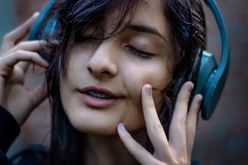 Dziewczyna w słuchawkach, z zamkniętymi oczami, słucha najbardziej wzruszające piosenki.