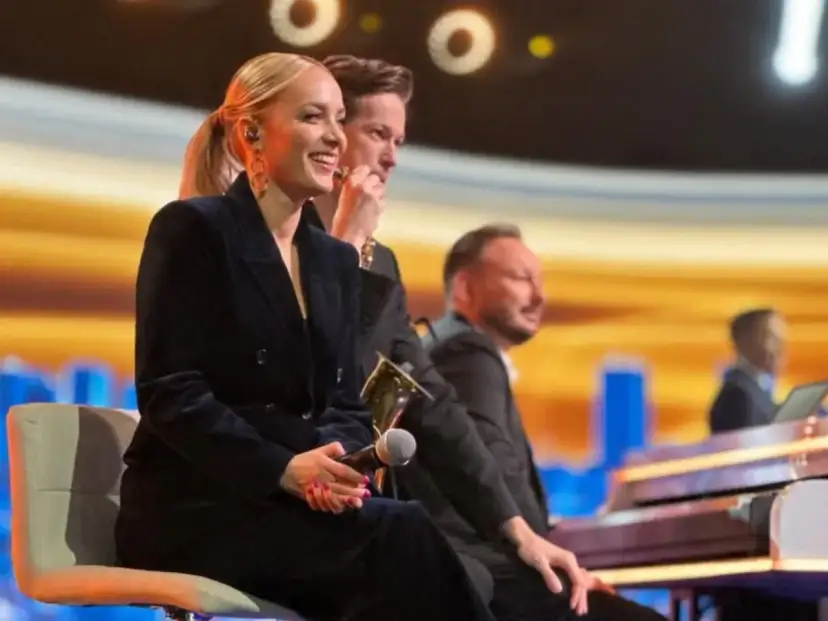 Uśmiechnięta wokalistka, która śpiewa w "Jaka to melodia", siedzi obok pianistów na scenie.