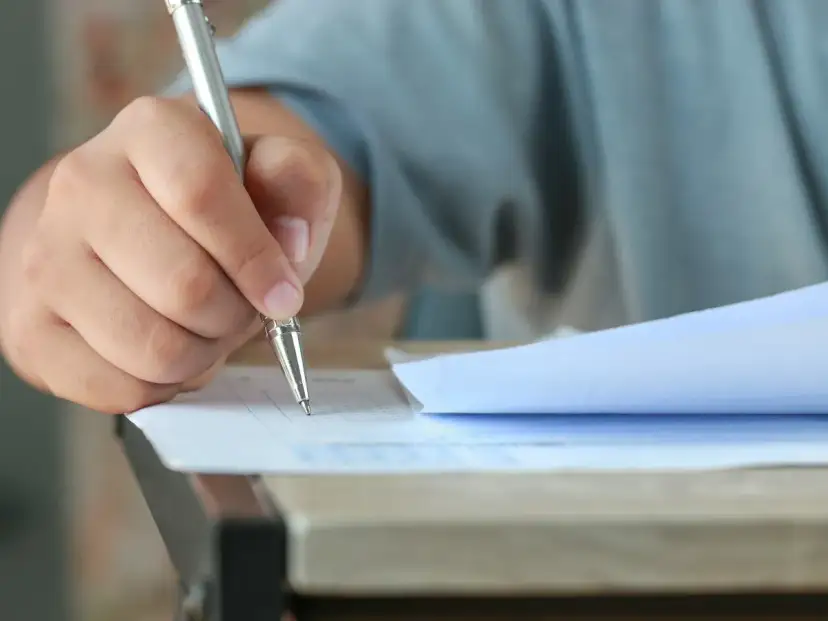 Dłoń trzymająca długopis, która wypełnia test. Czy przed jak również stawiamy przecinek, gdy piszemy.