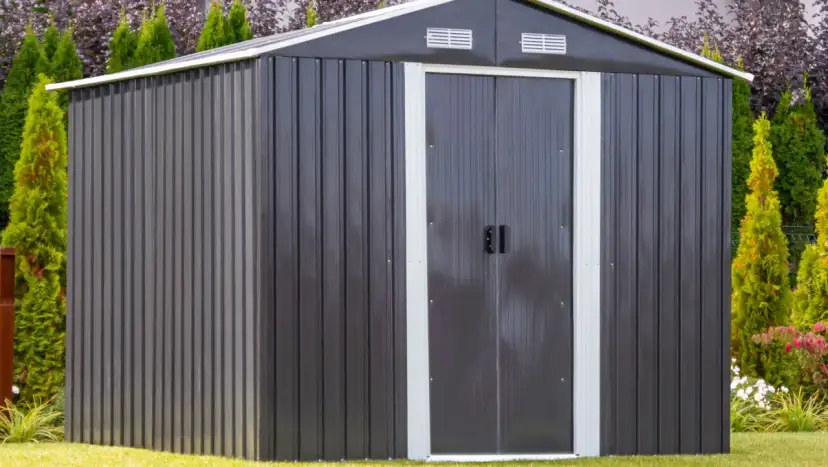 Nowoczesny, ciemnoszary domek narzędziowy z podwójnymi drzwiami, otoczony zielenią. Zastanawiasz się, czy domek narzędziowy trzeba zgłaszać?
