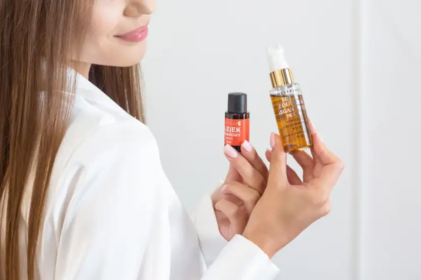 Kobieta prezentuje dwa produkty do pielęgnacji włosów, pokazując jak nakładać serum na włosy dla ich regeneracji i nawilżenia.