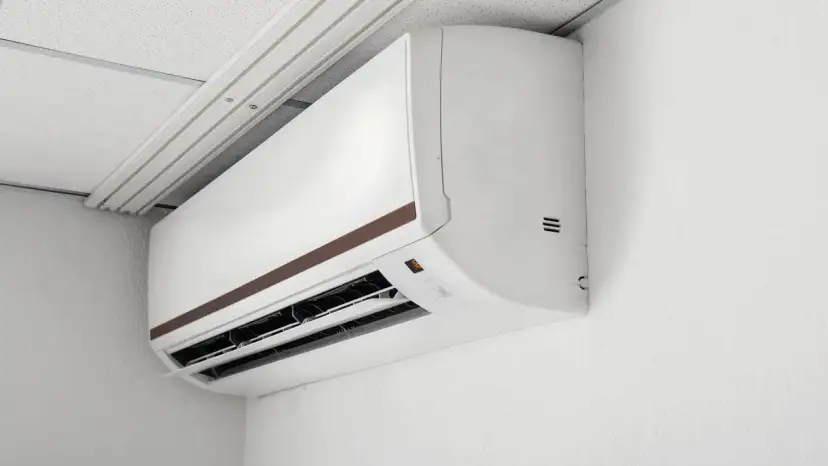 Biała jednostka klimatyzacyjna zamontowana na ścianie pod sufitem podwieszanym.