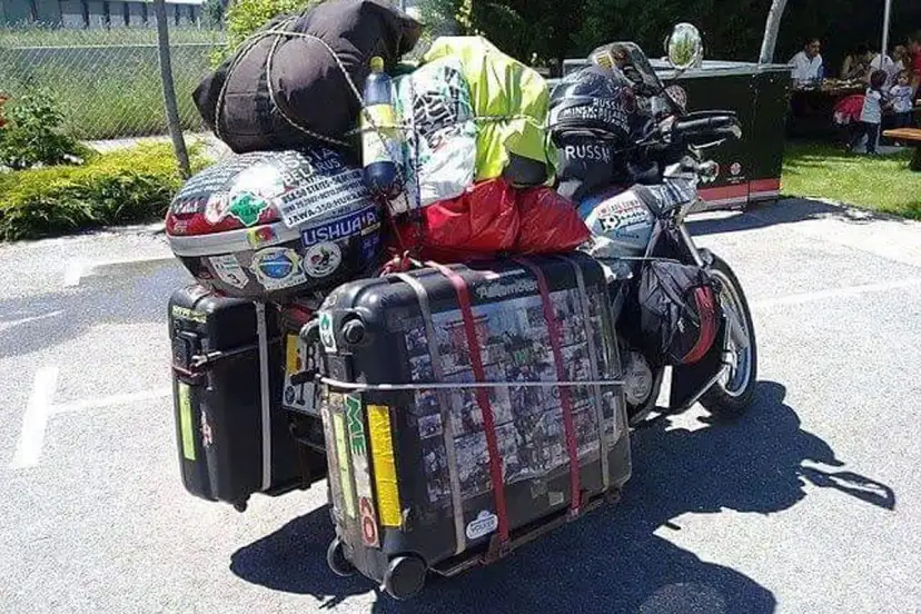Motocykl z bagażami, gotowy na wyprawę. Widać walizki, torby i kask. To wszystko, co zabrać na wyprawę motocyklową.