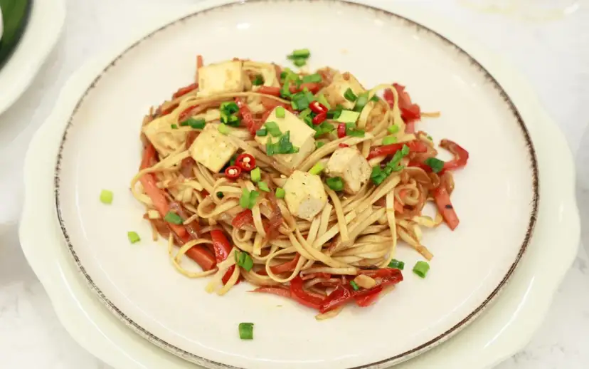 Pyszny makaron chow mein z kostkami tofu, papryką i szczypiorkiem.