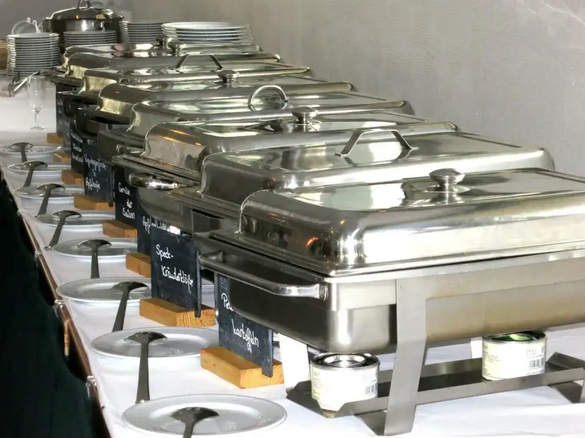 Długi rząd podgrzewaczy z jedzeniem, gotowych do serwowania. To świetny pomysł, jak otworzyć catering i zaimponować gościom.