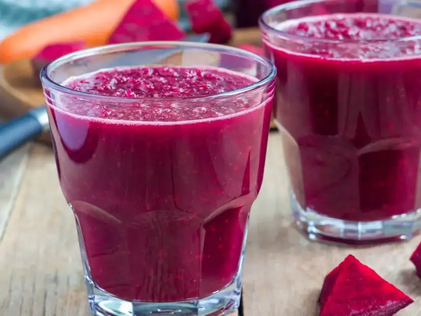 Intensywny, rubinowy koktajl z buraka na odchudzanie, orzeźwiający i pełen witamin. Obok leżą kawałki buraka i marchewki.