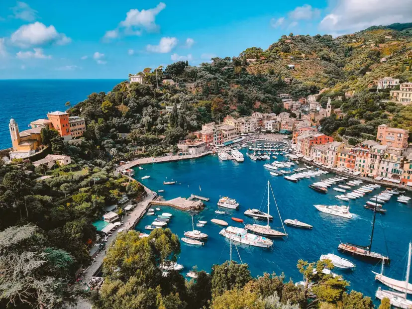 Malowniczy widok na zatokę z kolorowymi domami i licznymi łodziami. Tak właśnie wygląda Portofino, gdzie leży ten urokliwy włoski kurort.