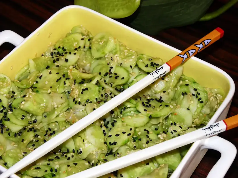 Pyszne ogórki po japońsku, posypane czarnym i białym sezamem, gotowe do jedzenia pałeczkami z motywem sushi.