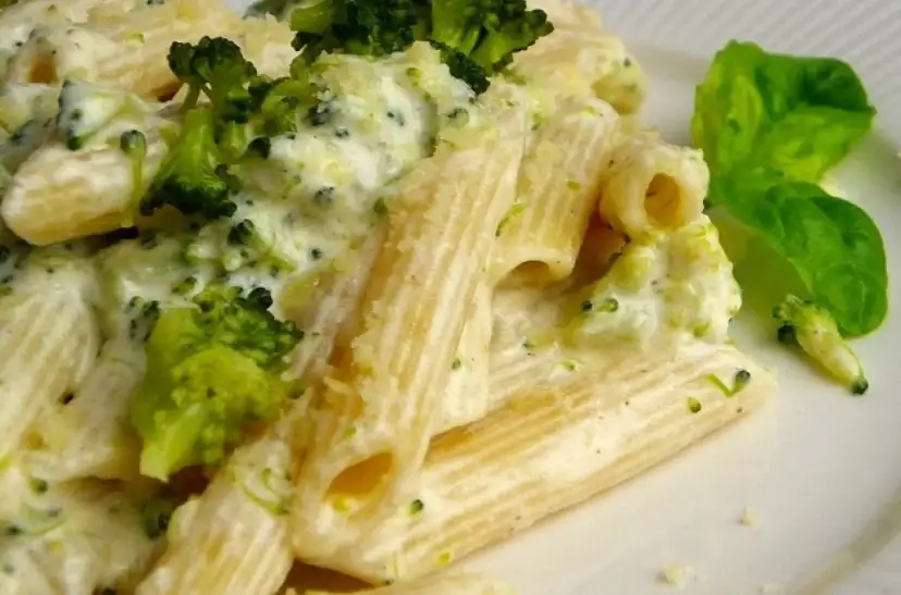 Penne z brokułami w kremowym sosie serowym, udekorowane listkiem bazylii. Pyszne danie, które zachwyci każdego smakosza.