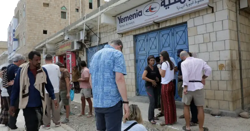 Ludzie stoją przed biurem Yemenia Airways. Czy Jemen jest bezpieczny? To pytanie zadają sobie podróżni, obserwując codzienne życie w tym kraju.