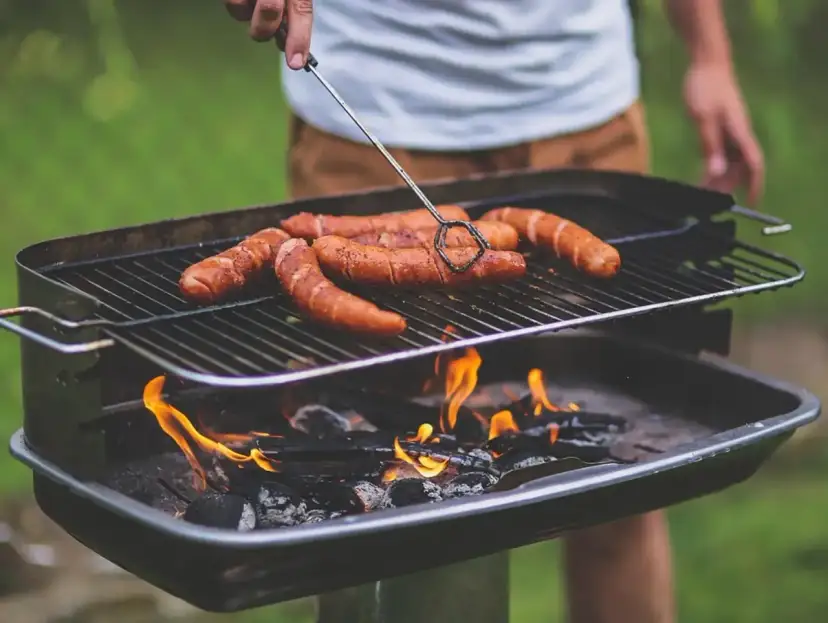 Kiełbaski skwierczą na grillu, idealne miejsce, gdzie zrobić grilla w ogrodzie.