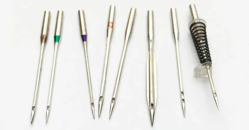 Zestaw igieł do maszyny, w tym igła 90/14 do szycia średnich materiałów. Różne kolory na trzonkach oznaczają rozmiar.