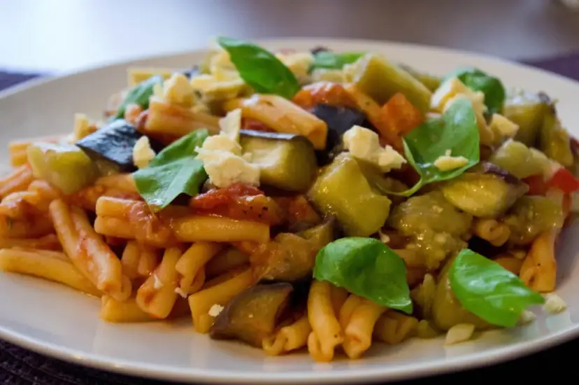 Pyszne danie z makaronem, bakłażanem i pomidorami, posypane serem i bazylią. Idealne na Pasta alla Norma przepis.