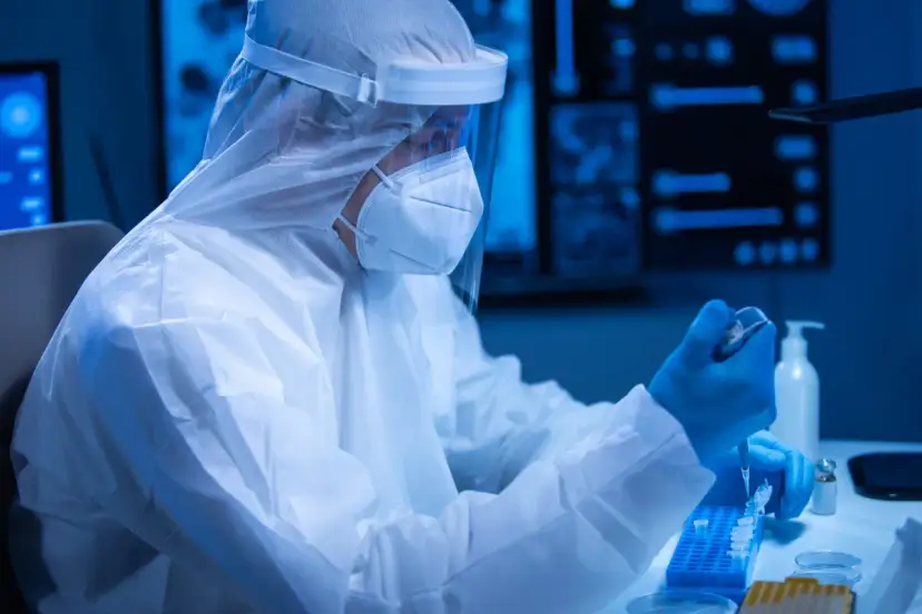 Badacz w kombinezonie ochronnym pracuje w laboratorium, przygotowując próbki. Czas oczekiwania na wynik badania PCR może być różny.