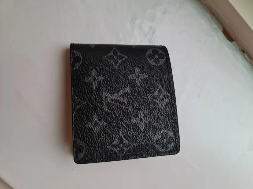 Czarny portfel Louis Vuitton z monogramem na jasnym tle.