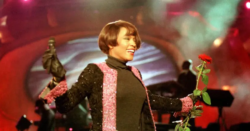 Whitney Houston z mikrofonem i czerwoną różą podczas niezapomnianego koncertu w Polsce.