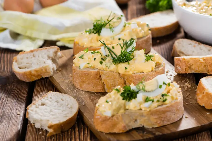 Kromki chleba z kremową pastą jajeczną na różne sposoby, ozdobione ziołami. Idealne na szybkie śniadanie lub przekąskę.
