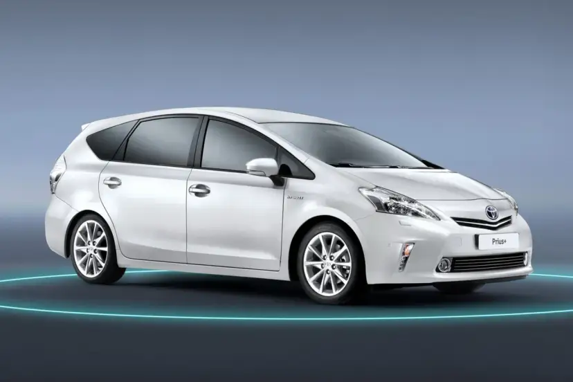 Biały Toyota Prius+ na tle niebieskim. To auto hybrydowe, które oferuje przestronne wnętrze, idealne dla rodziny. Ile miejsc ma ten model?