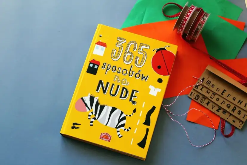 Żółta książka "365 sposobów na nudę" z zebrą, biedronką i literami.