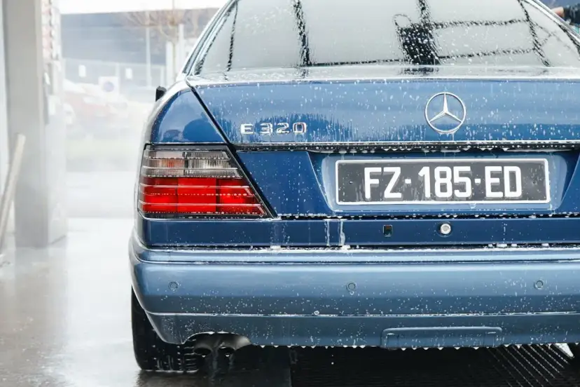 Tylna część niebieskiego Mercedesa E320 pokryta pianą, podczas mycia na myjni.