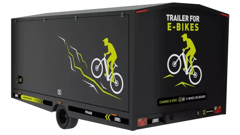 Czarna rowerowa przyczepa kempingowa z grafiką rowerzysty na górskim szlaku. Napis "TRAILER FOR E-BIKES" i "CHARGE & RIDE x8 E-BIKES ON BOARD".
