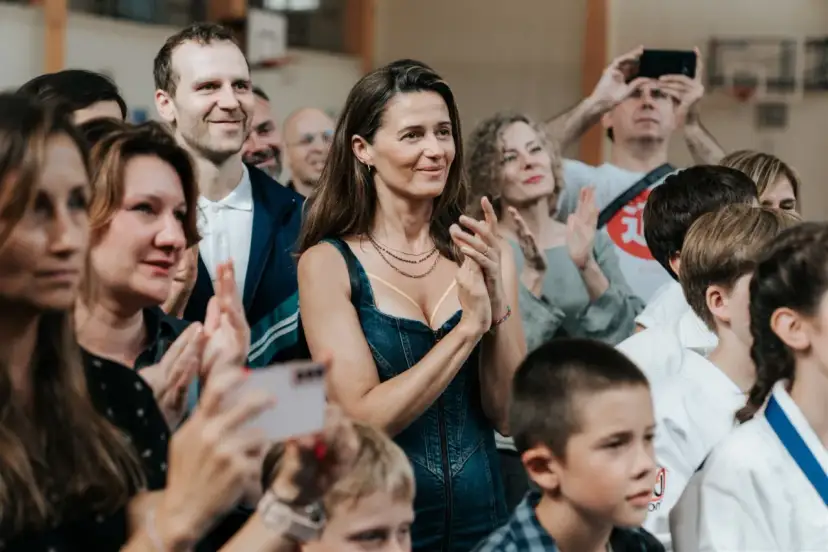 Agnieszka Grochowska z uśmiechem klaszcze, otoczona ludźmi na widowni.