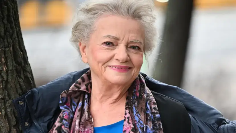 Uśmiechnięta Anna Seniuk, ikona polskich filmów, seriali i programów, w kolorowym szalu i granatowej kurtce.