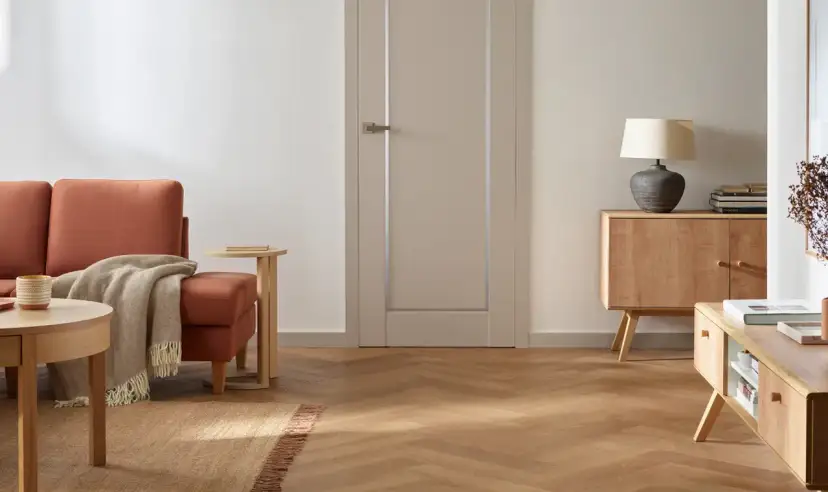 Nowoczesne wnętrze z pomarańczową kanapą, drewnianymi meblami i jasnymi drzwiami.