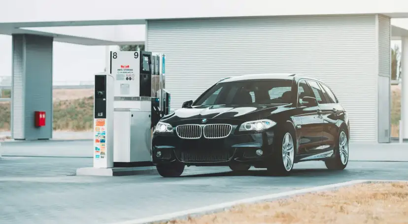 Czarne BMW na stacji paliw. Przykład, jak odliczyć 50% VAT od paliwa, może być związany z kosztami podróży służbowych.