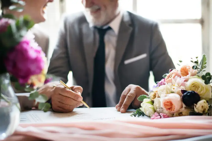 Para 36 rocznica ślubu nazwa, pan młody podpisuje dokument złotym piórem. Obok bukiet kwiatów.