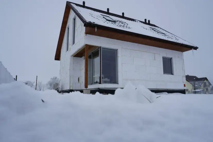 Dom szkieletowy w zimowej scenerii, z widocznym grubym ociepleniem ścian.