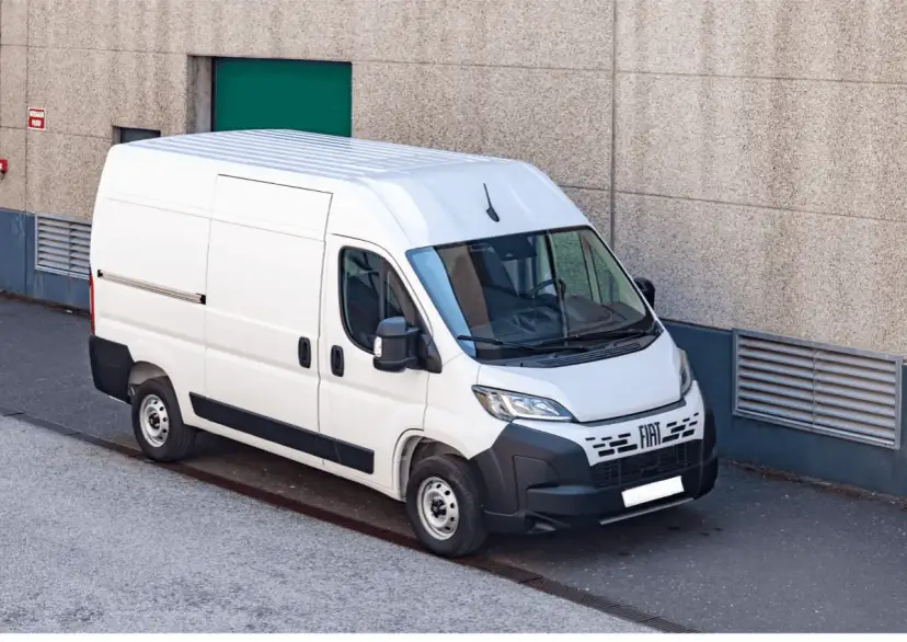 Biały bus 9 osobowy Fiat Ducato, zaparkowany przy betonowej ścianie. Zastanawiasz się, ile pali bus 9 osobowy?