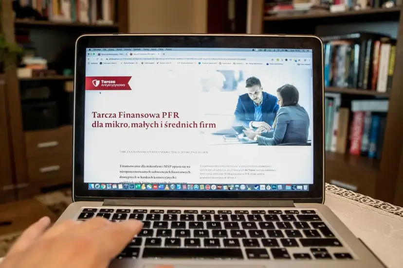 Szukasz informacji, jak sprawdzić czy firma dostała dofinansowanie z tarczy? Na ekranie laptopa wyświetla się strona o Tarczę Finansową PFR dla mikro, małych i średnich firm.