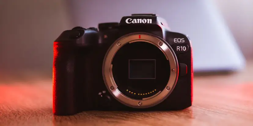 Canon EOS R10 w teście. Ciemna obudowa aparatu z czerwonym podświetleniem, widoczny bagnet obiektywu.