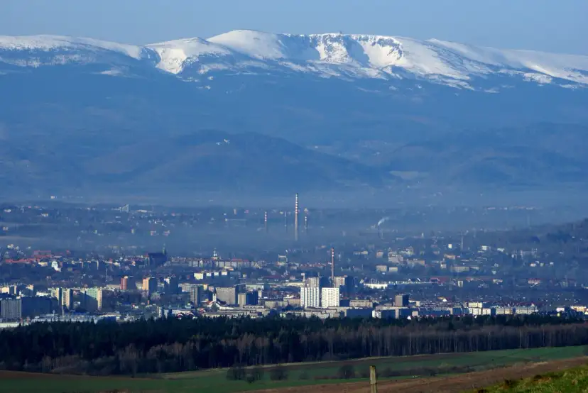 Widok na miasto u podnóża ośnieżonych gór. Trudno oszacować, ile jelenia góra ma mieszkańców, ale miasto jest spore.