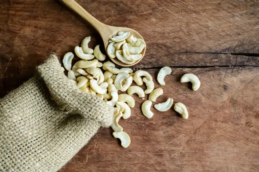 Orzechy nerkowce właściwości: garść zdrowia wysypana z worka na drewniany stół.