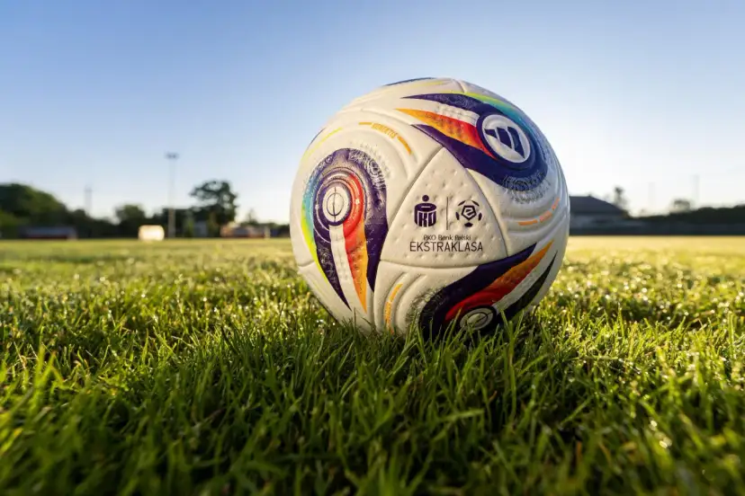 Piłka PKO Bank Polski Ekstraklasa leży na mokrej trawie. Ile meczy zostalo w ekstraklasie?